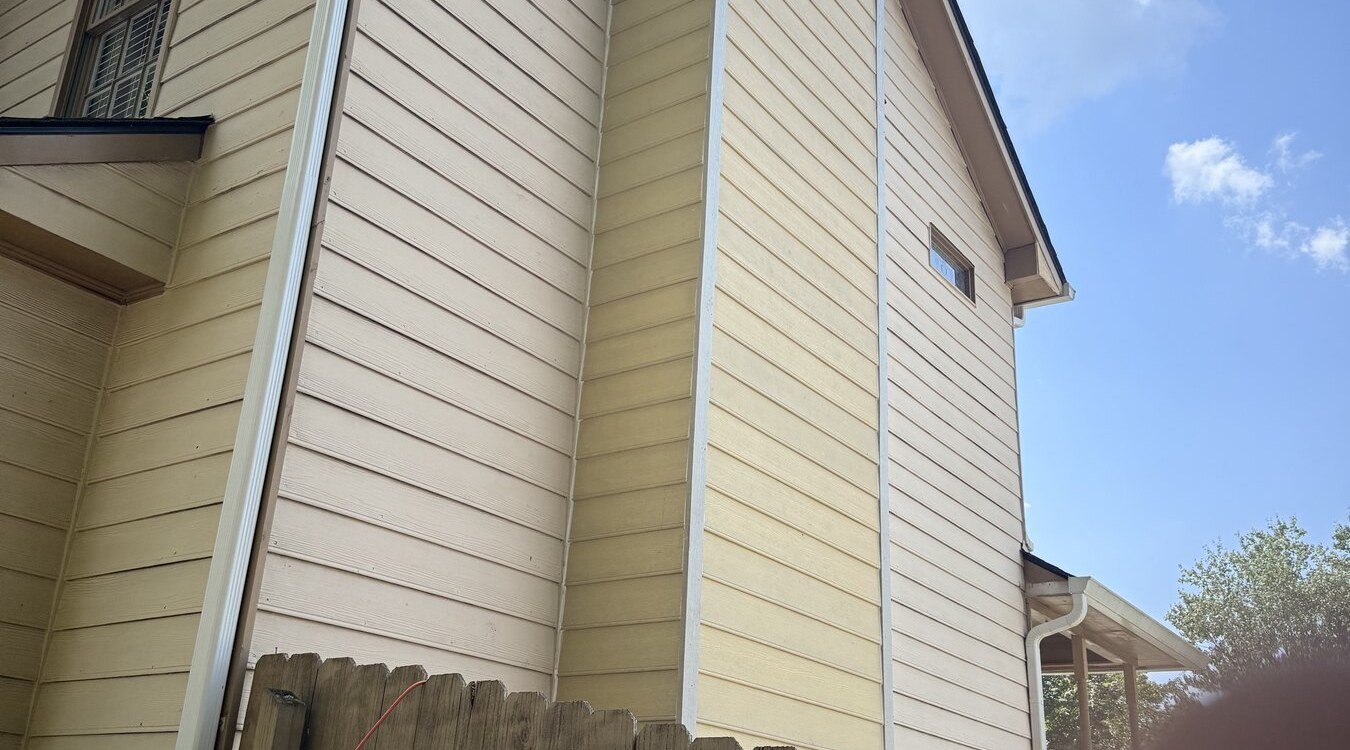 Replaced cream siding and trim on a two-story gable end and chimney chase