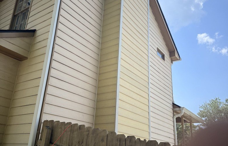 Replaced cream siding and trim on a two-story gable end and chimney chase