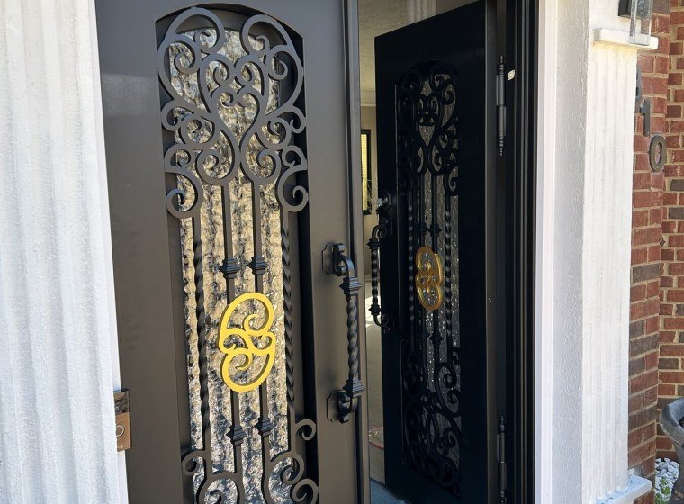 Ornate wrought iron and glass front door set in a brick entryway